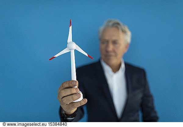 Senior businessman holding wind turbine model