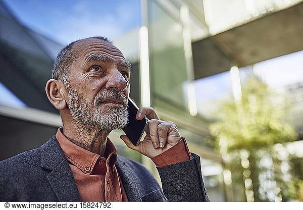 Senior businessman in the city  talking on the phone