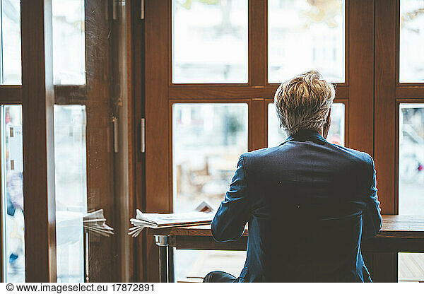 Senior businessman looking through window in cafe