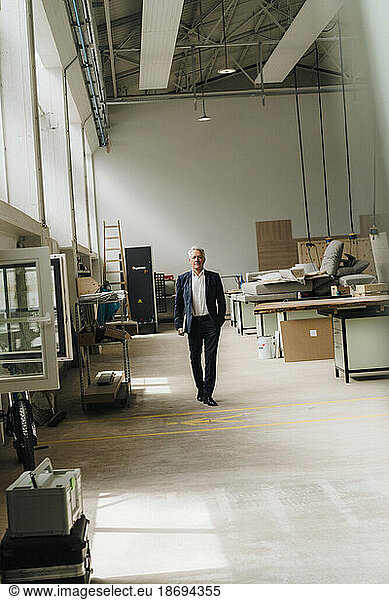 Senior businessman walking on production floor in factory