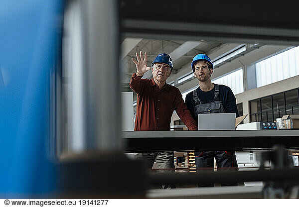 Senior businessman with colleague examining machinery at factory