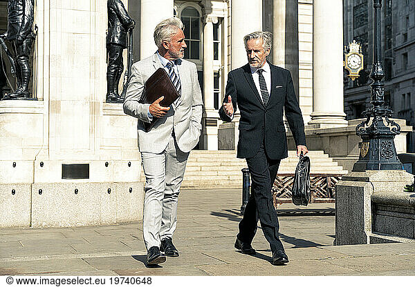 Senior businessmen walking and having discussion together on sunny day