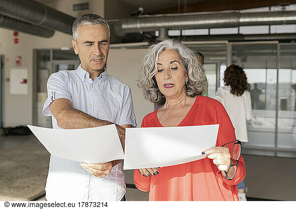 Senior businesswoman discussing over document with colleague in office