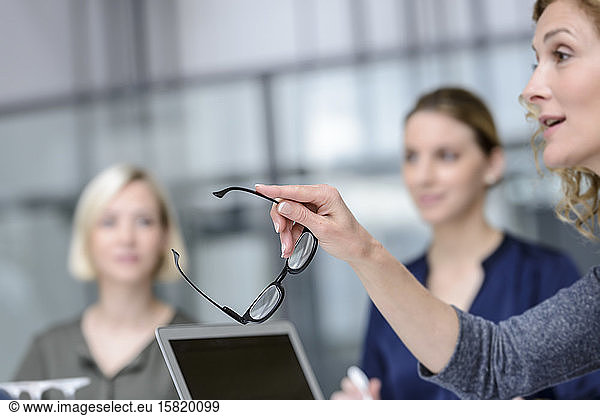 Senior businesswoman  gesturing in a meeting  holding her glasses