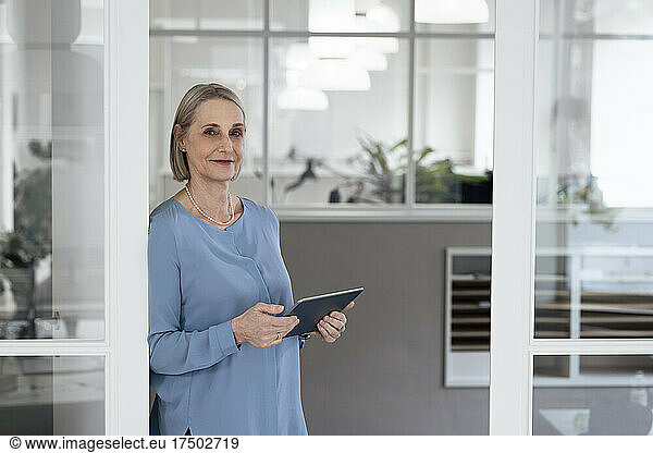 Senior businesswoman holding tablet PC at doorway