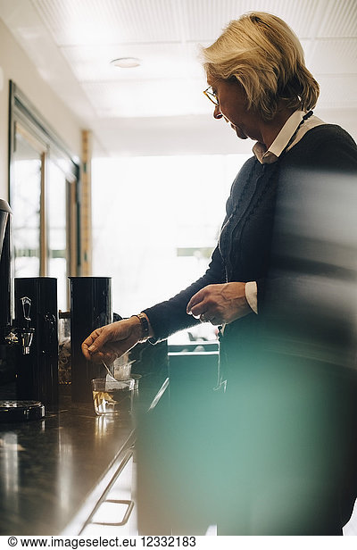 Senior businesswoman making tea at office canteen