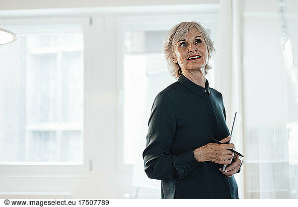Senior businesswoman with note pad standing at workplace