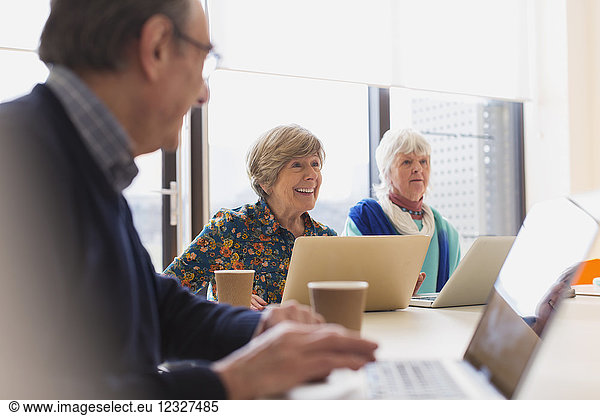 Senior businesswomen using laptops in conference room meeting