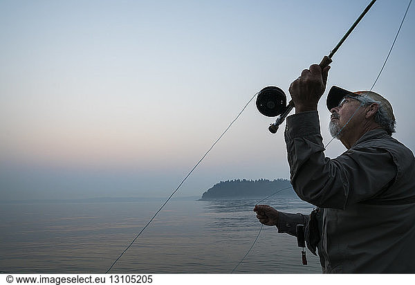 Senior Caucasian male fly fishing for salmon and sea run cutthroat trout off the coast