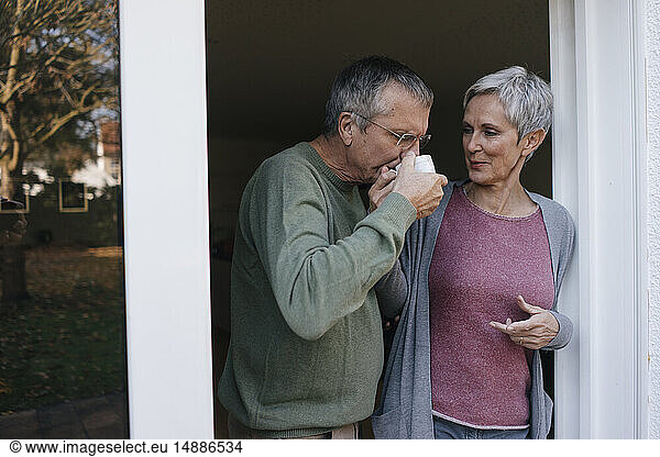 Senior couple drinking coffee at terrace door