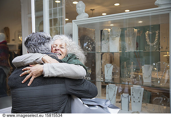 Senior couple hugging  window shopping at jewelry storefront