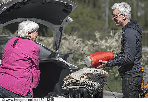 Senior couple loading car boot