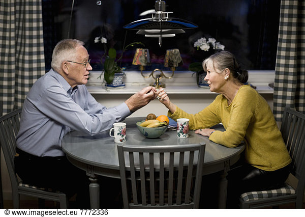 Senior couple looking at each other while holding hands over dining table