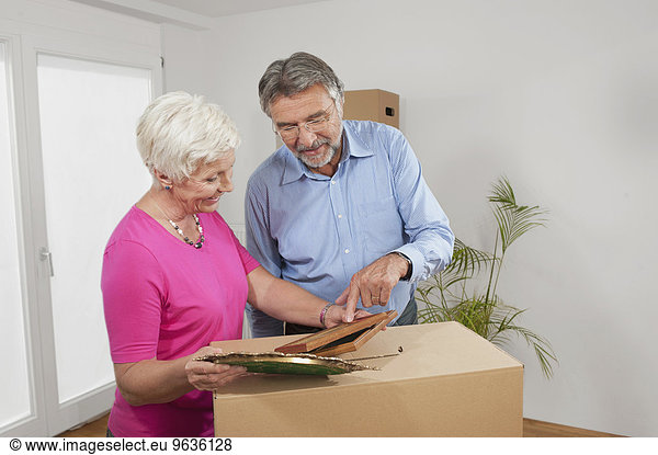 Senior couple looking at picture frames in new apartment