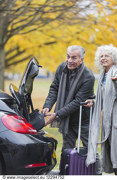 Senior couple removing luggage from car trunk