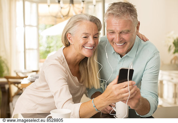 Senior couple sharing mp3 player in domestic kitchen