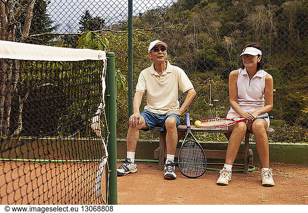 Senior couple sitting on bench at tennis court