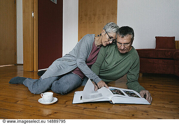 Senior couple sitting on the floor at home looking at photo album