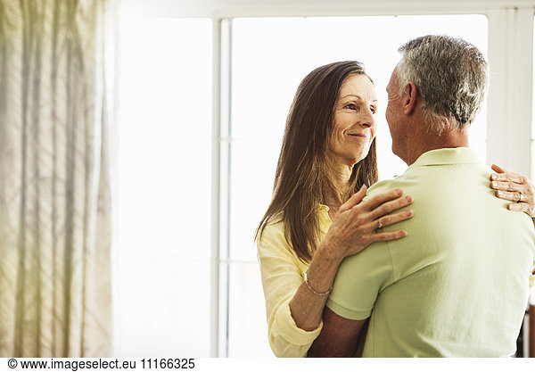 Senior couple standing indoors  embracing.