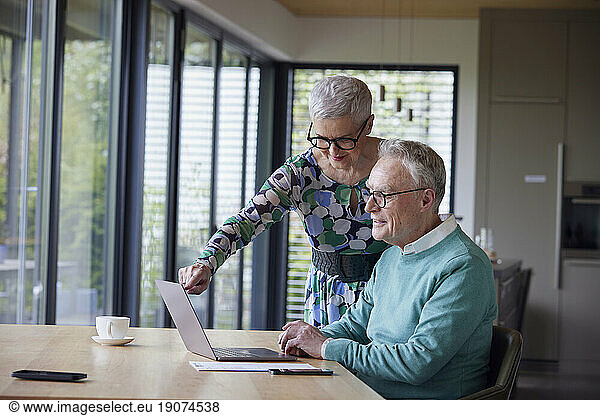 Senior couple using laptop at table at home