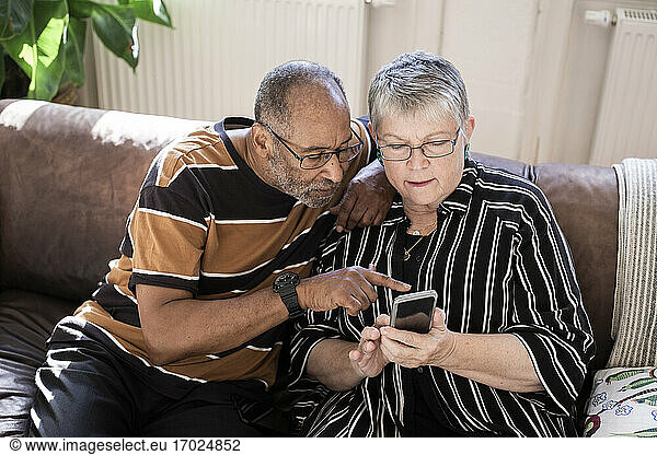Senior couple using smart phone in living room