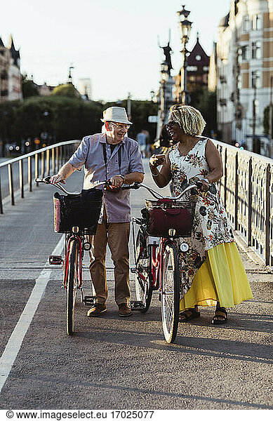 Senior couple with bicycle on bridge during weekend