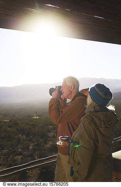 Senior couple with camera on sunny safari balcony