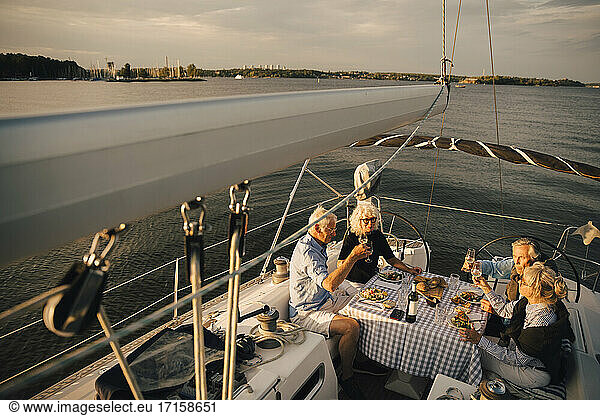 Senior couples toasting wineglasses while spending leisure time in boat