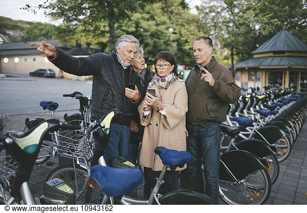 Senior couples using mobile phones at bicycle parking station