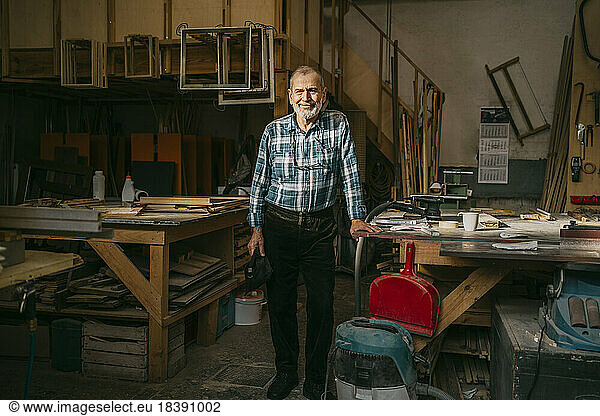 Senior craftsman standing near workbench at carpentry workshop