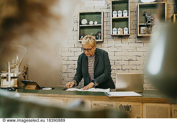 Senior female entrepreneur examining documents at decor shop