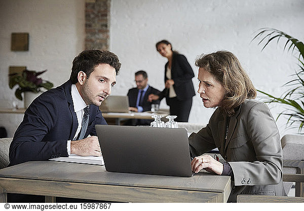 Senior female lawyer discussing over laptop with young businessman during meeting at office