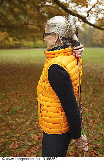 Senior female nordic walker exercising with walking poles in park