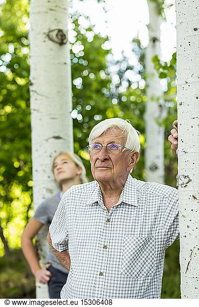 Senior grandfather with his teen granddaughter in aspen forest