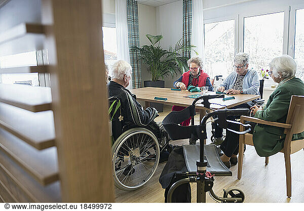 Senior inhabitants playing board game in rest home