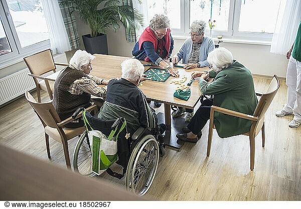 Senior inhabitants playing board game in rest home