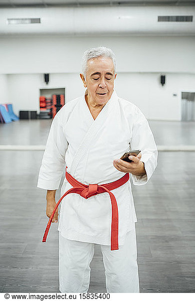 senior Karate master using mobile cell phone