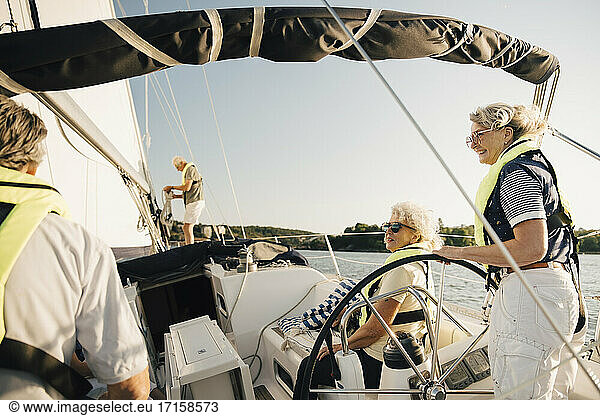 Senior male and female friends spending leisure time in sailboat on sunny day