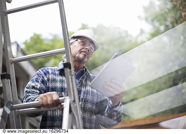 Senior male construction foreman using digital tablet on ladder
