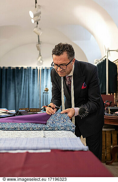 Senior male tailor comparing fabrics