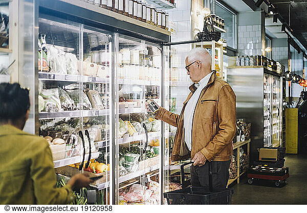 Senior man analyzing jar at grocery store