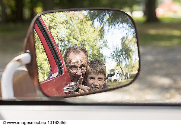 Senior man and grandson reflected in truck wing mirror