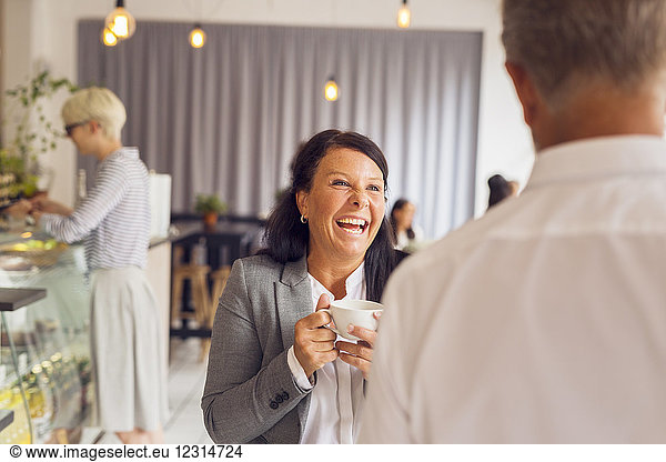 Senior man and mature woman laughing in cafe
