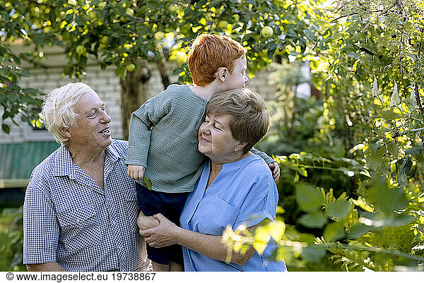 Senior man and woman with grandson in garden