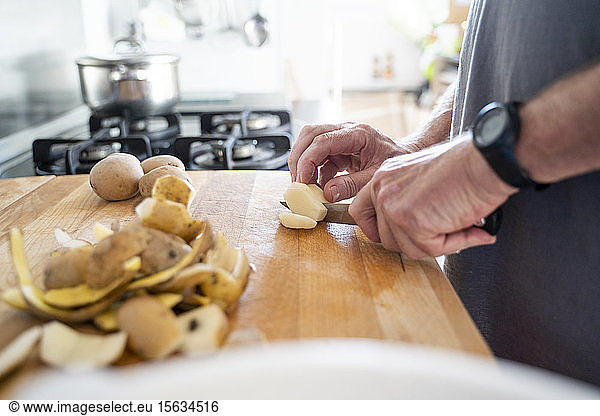 Senior man cutting potatoes on the chopping board