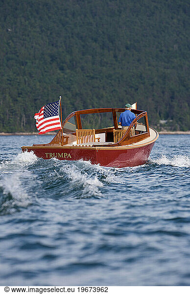 Senior man drives a power yacht in Somes Sound  Maine.