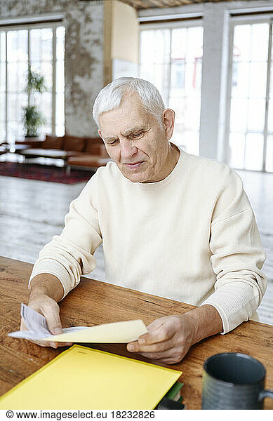 Senior man examining financial bills at home
