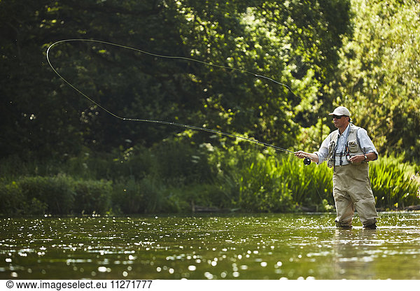 Senior man fly fishing at summer river