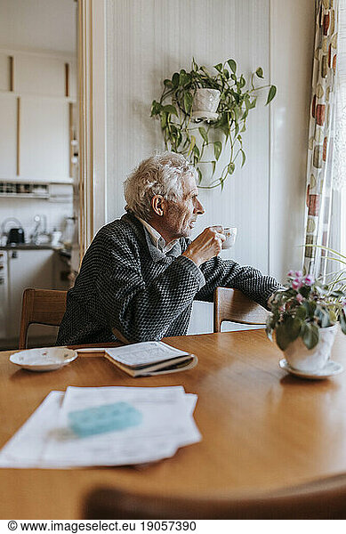 Senior man having tea while sitting at dining table in home