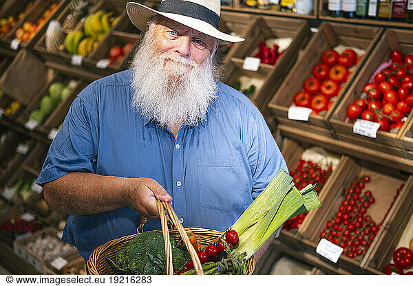 Senior man holding basket of vegetables at farmer's market